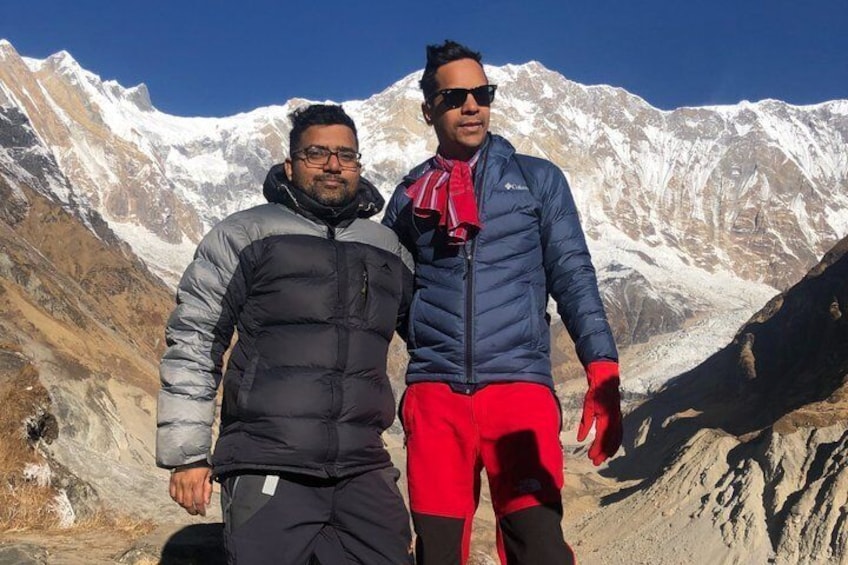Two people standing in a mountainous area with snow-capped peaks in the background. 3