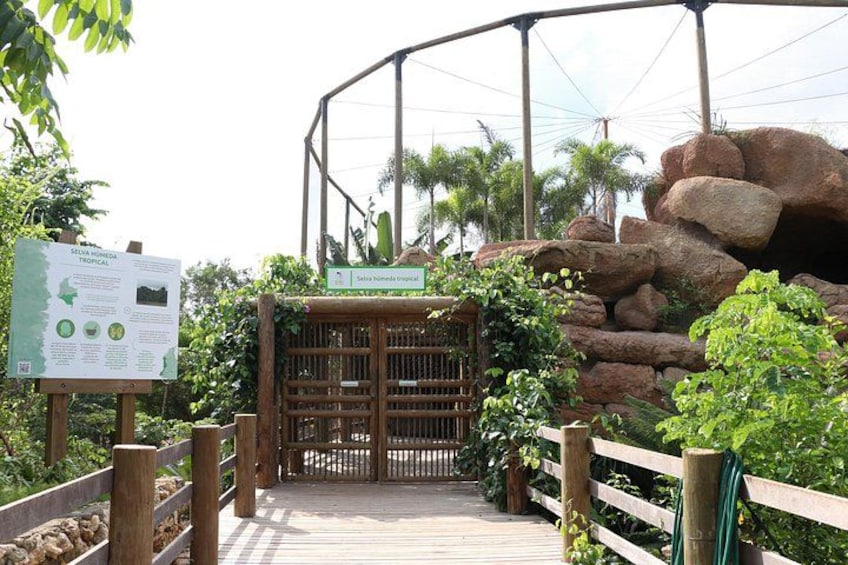 A wooden pathway leading to a gate with a signboard, surrounded by rocks and greenery. 1