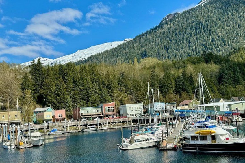 Ein Hafen mit Booten, Gebäuden und einem schneebedeckten Berg im Hintergrund. 3