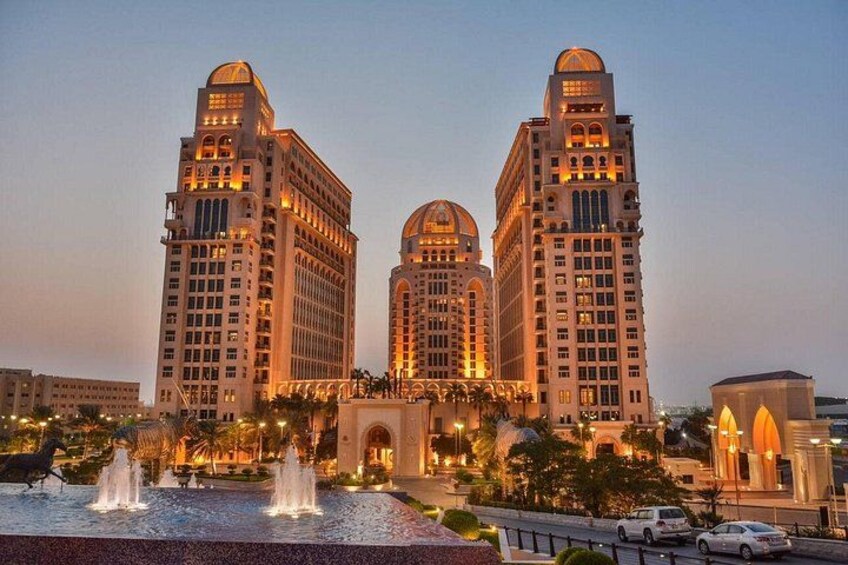 Een groot, verlicht hotel met drie torens en een fontein op de voorgrond. 4