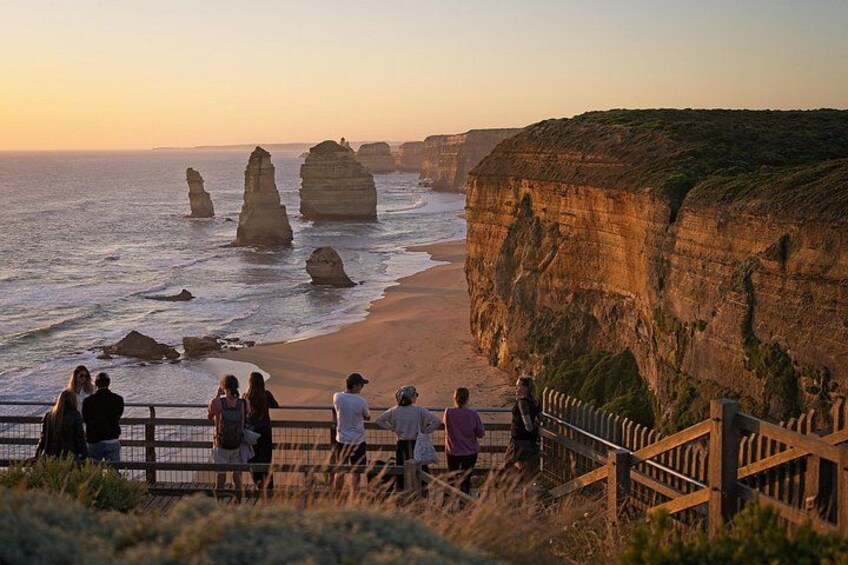 A coastal landscape with rock formations, a sandy beach, and a wooden fence. 1