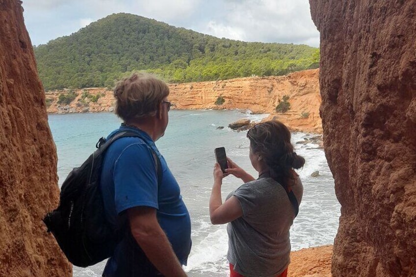 Dos personas fotografiando un paisaje costero con acantilados y una masa de agua. 1