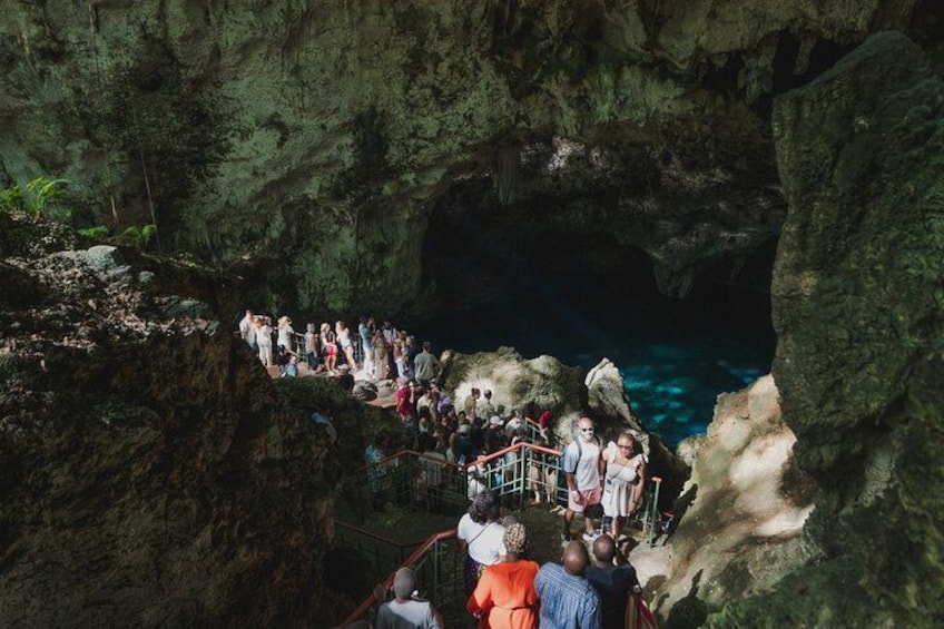 A group of people standing on a rocky ledge overlooking a cave entrance. 3