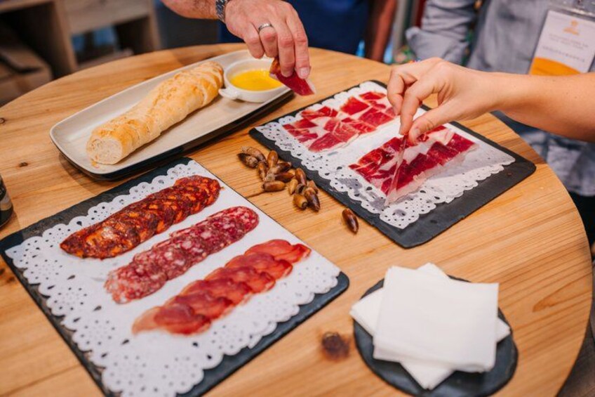 A table with various food items including bread, sliced meats, and a small bowl of sauce. 2