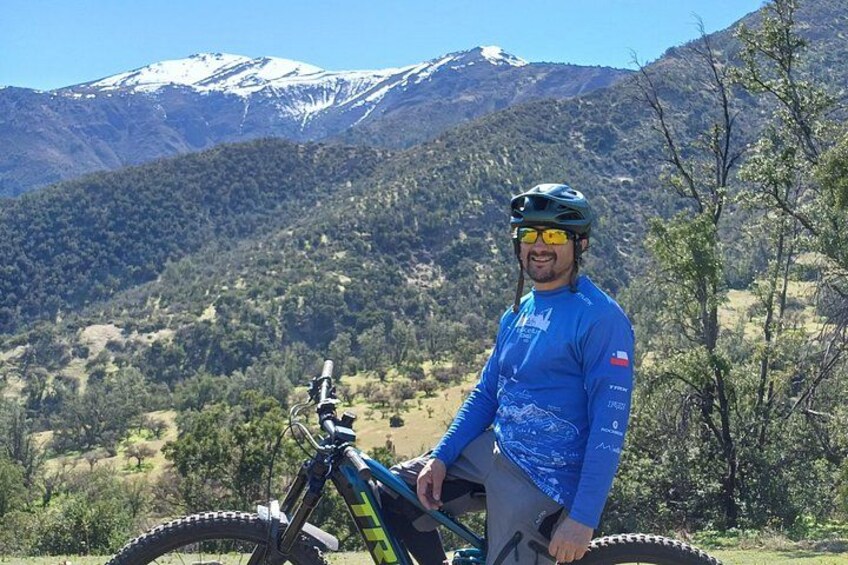 Een persoon met een mountainbike in een bergachtig landschap met besneeuwde toppen. 3