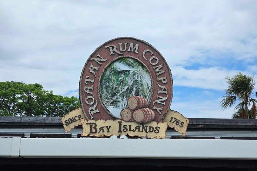 Skilt for Roatan Rum Company med et vintage design, inklusive et billede af et romfade og palmer. 4