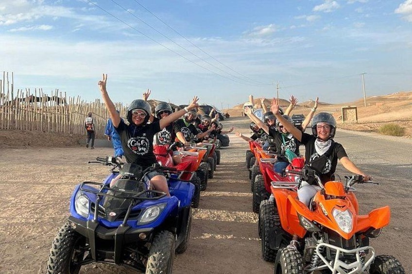 Un groupe de personnes conduisant des quads sur un chemin de terre, avec une clôture en bois et un paysage désertique en arrière-plan. 4