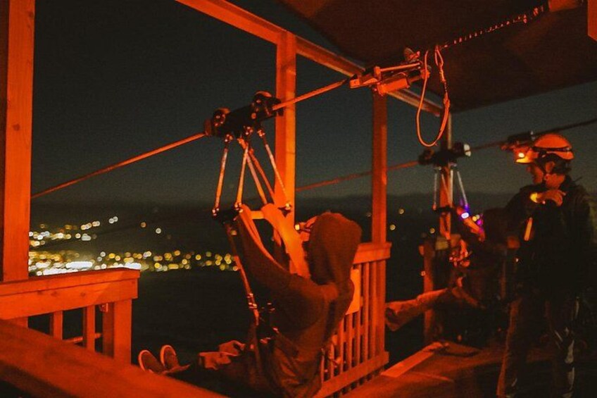 A person operating a telescope on a balcony at night. 3