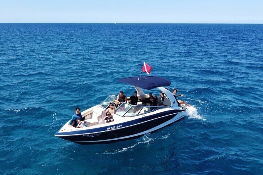 Un motoscafo con una bandiera rossa a prua, persone a bordo e l'oceano sullo sfondo. 5