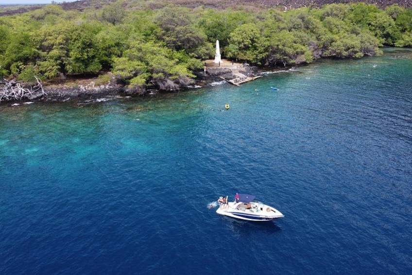 Un bateau sur une mer bleue et limpide, avec un phare sur une côte rocheuse. 3