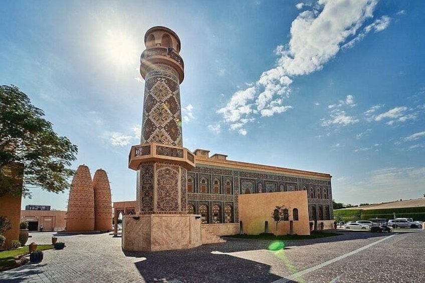 A mosque with a tall minaret, a courtyard, and a building with intricate tile work. 1