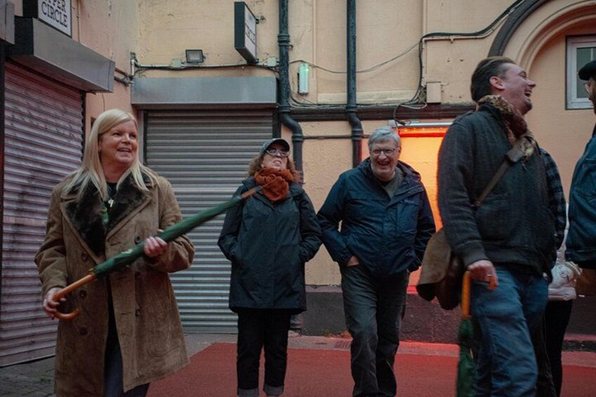 Een groep mensen loopt over straat, sommigen met paraplu's. 5