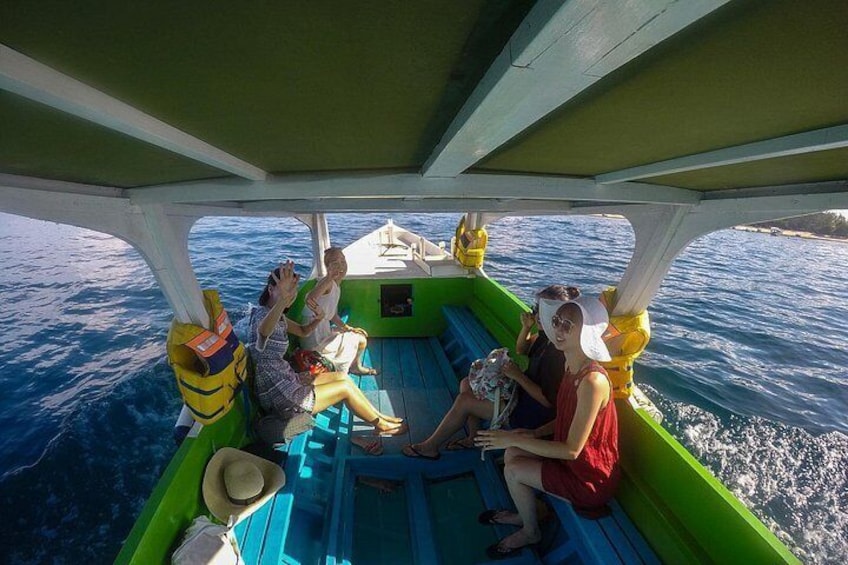 Un bote con gente sentada en la cubierta, usando chalecos salvavidas, y el océano al fondo. 4