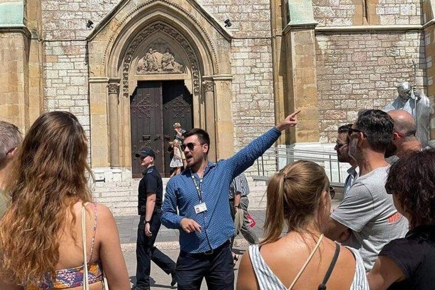 Un groupe de personnes s’est rassemblé devant un bâtiment historique doté d’une grande entrée en arc de cercle. 1