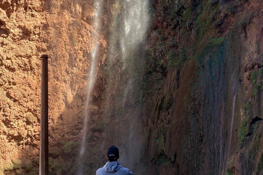 Une personne se tient devant une cascade, avec une falaise rocheuse en arrière-plan. 3
