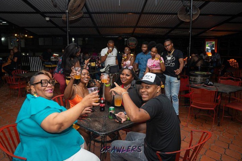 A group of people toasting at a table in an outdoor setting with chairs and tables. 2