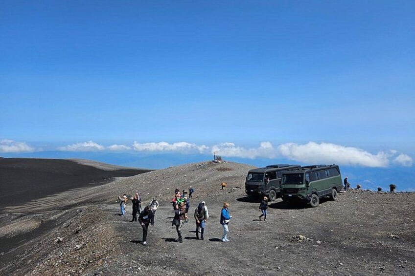 A group of people on a rocky terrain with a green vehicle and a clear sky. 5