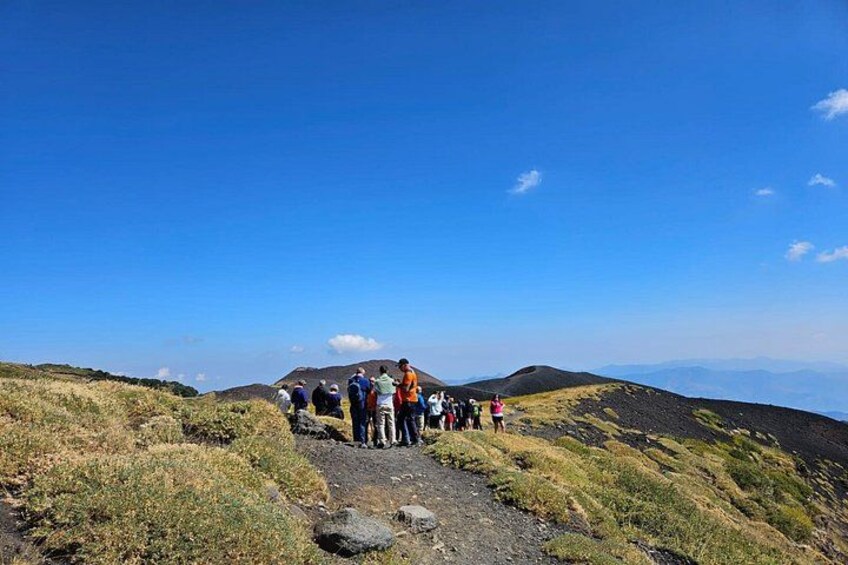 A group of people standing on a mountain trail with a clear sky. 2