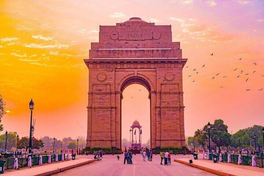 The India Gate with a sunset sky, surrounded by people and greenery. 5