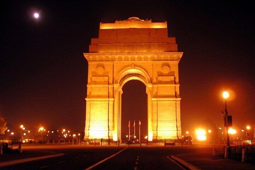 A large illuminated archway at night with a full moon in the background. 4