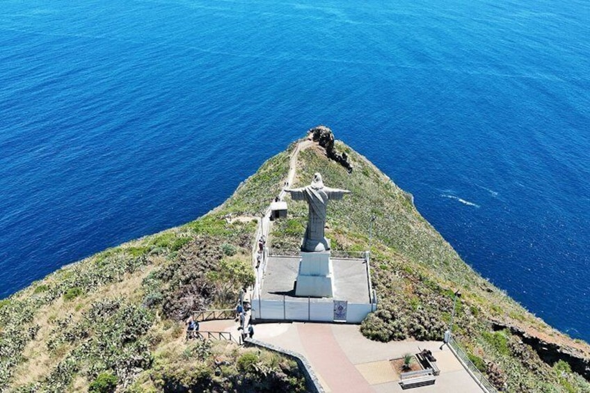 Un mirador costero con una estatua, un sendero empedrado y terreno rocoso. 2