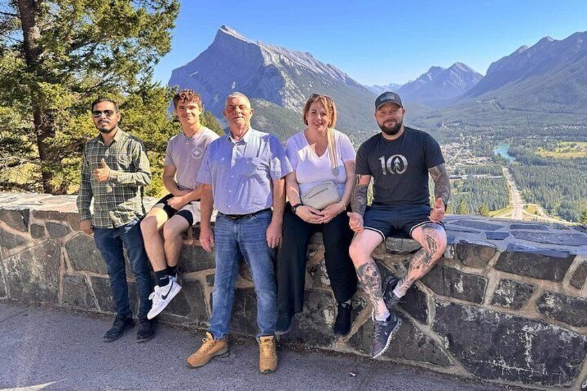 Un groupe de personnes est assis sur une corniche de pierre, avec un paysage montagneux en arrière-plan. 5