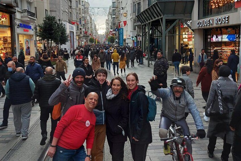 Une rue animée en ville, avec des piétons, des boutiques et un vélo. 2