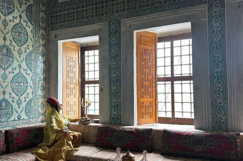 A room with patterned walls, a wooden door, and a window with a view. 2