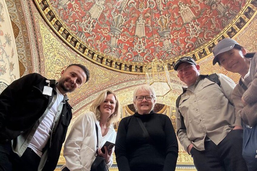 Un groupe de personnes se trouve dans une pièce dont le plafond est orné de décorations élaborées. 4