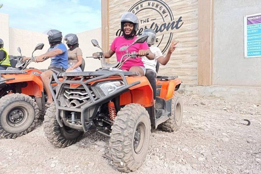 A person on an orange ATV in front of a building with a sign that reads 'The Old Nungwi.' 1