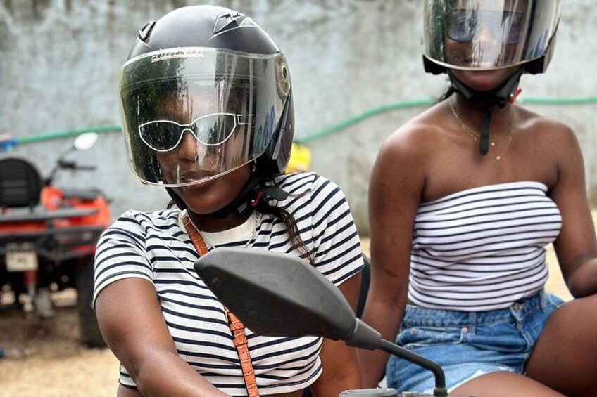 Two people on a motorcycle, one wearing a helmet and sunglasses, and the other in a striped top. 4