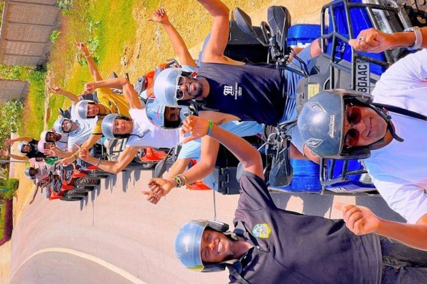A group of people on a race track, wearing helmets and racing suits, with a blue car in the background. 3