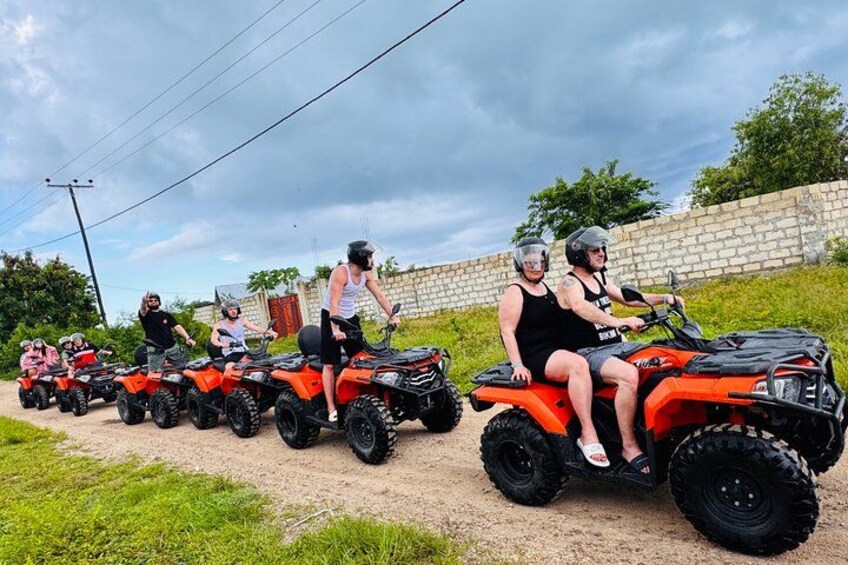 A group of people riding ATVs on a dirt path. 1