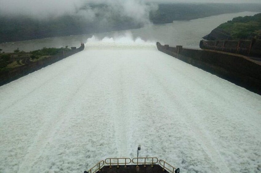 A dam releasing water, a boat in the foreground, and a cloudy sky. 1