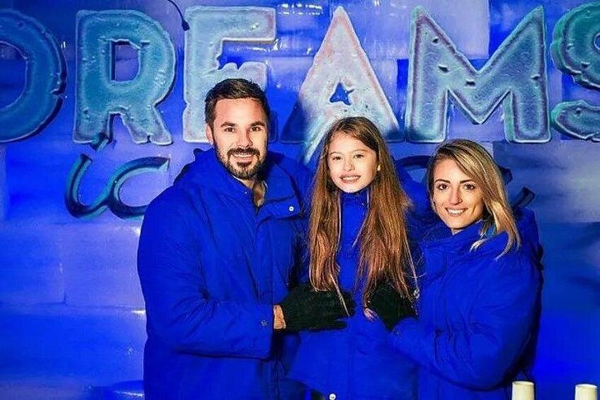 Three people in blue jackets standing in front of a blue background with the word 'DREAMS' visible. 3
