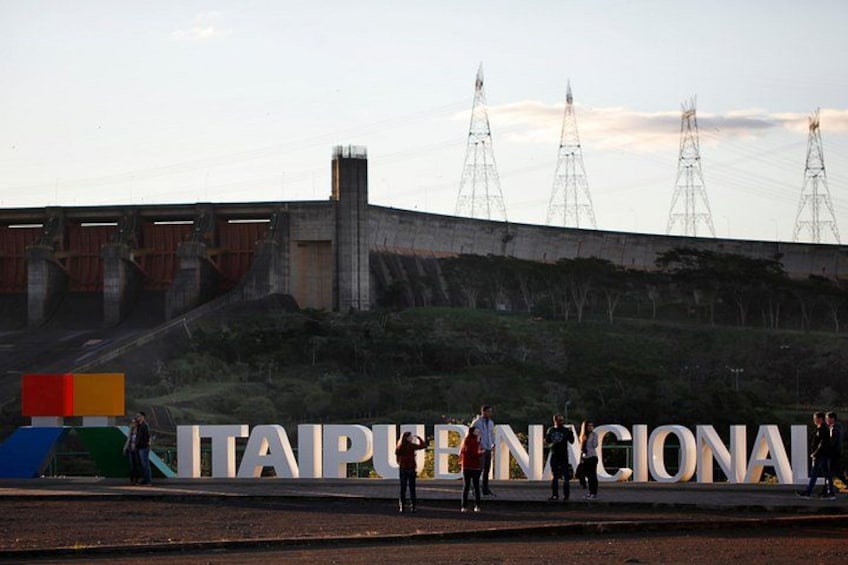 A large sign with 'TAIPU EN CIONAL' and a construction site with a bridge and power lines in the background. 1