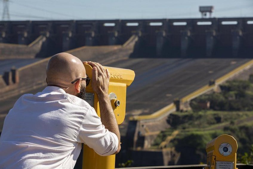 A man using binoculars, overlooking a bridge with multiple lanes. 3
