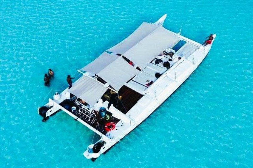 Een witte boot met een vlak dek en een klein hutje, drijvend in helder turquoise water. 4