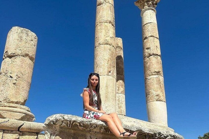 A person sitting on a stone structure with ancient columns in the background. 3