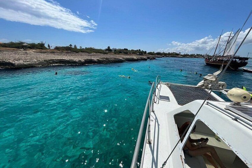 A boat on turquoise water with a clear sky and distant shoreline. 5