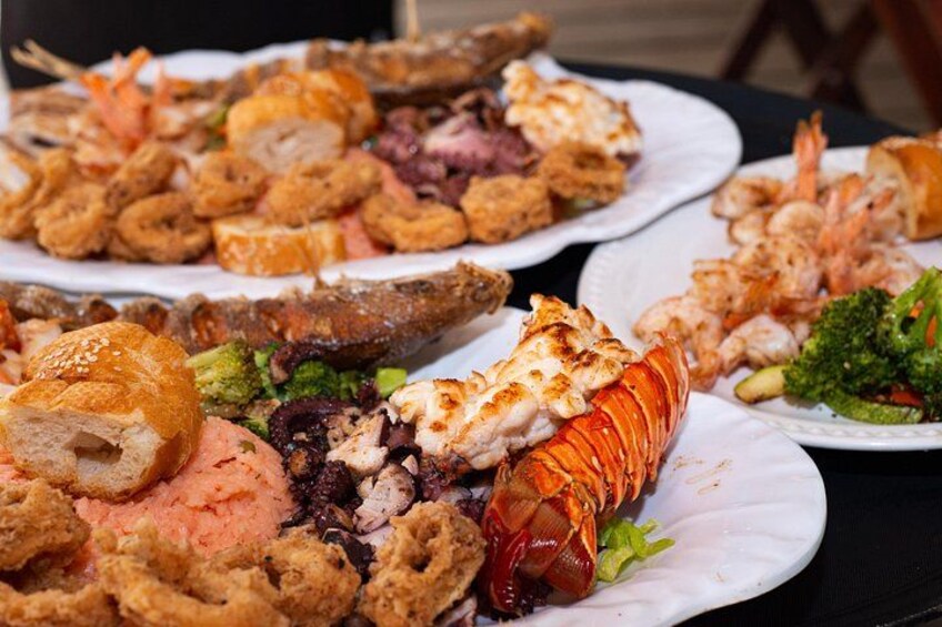 A variety of seafood dishes on plates, including shrimp, lobster, and fried items. 2