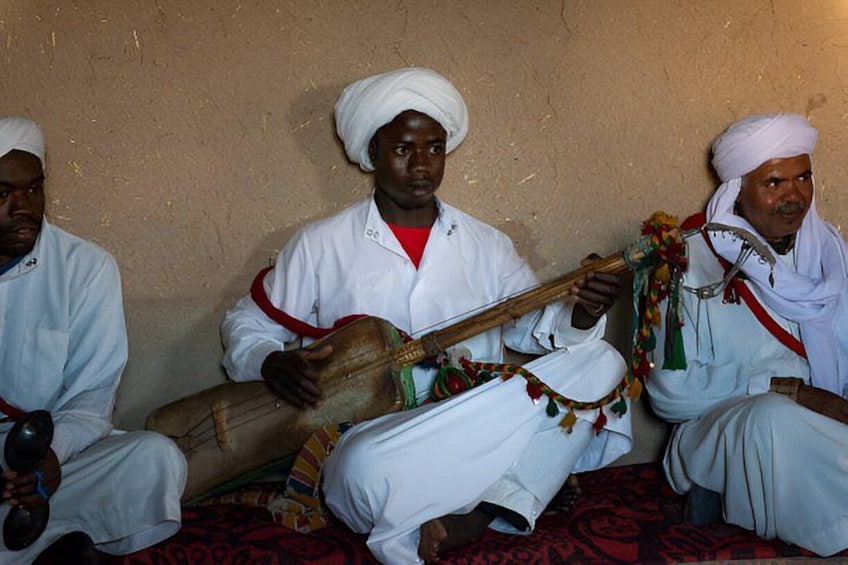 Three men seated, playing traditional string instruments. 2