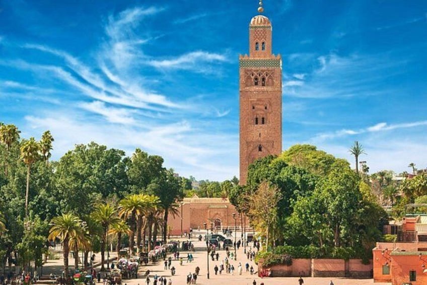 A tall tower with a minaret, surrounded by palm trees and a bustling square. 4