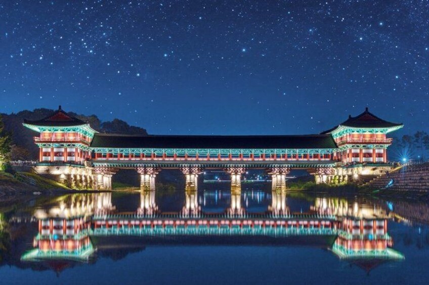 A traditional Korean palace with a reflection in the water under a starry night sky. 2