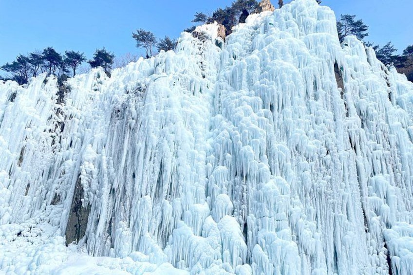 A large ice formation on a mountain with trees in the background. 3