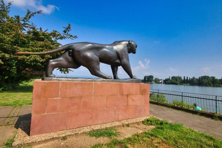 Een bronzen beeld van een beer en een jong beer op een bakstenen sokkel aan een meer. 4