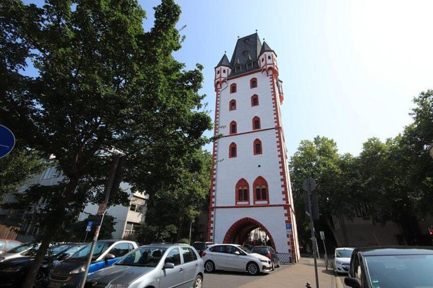 Een hoge toren met rode en witte strepen, omringd door bomen en geparkeerde auto's. 5