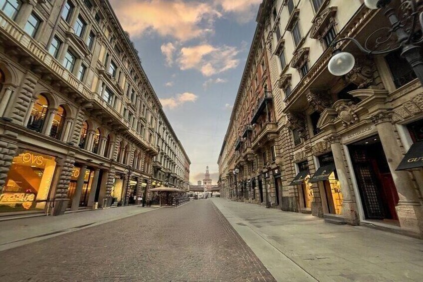 A wide street lined with historic buildings, a clear sky, and a distant view of a domed structure. 4