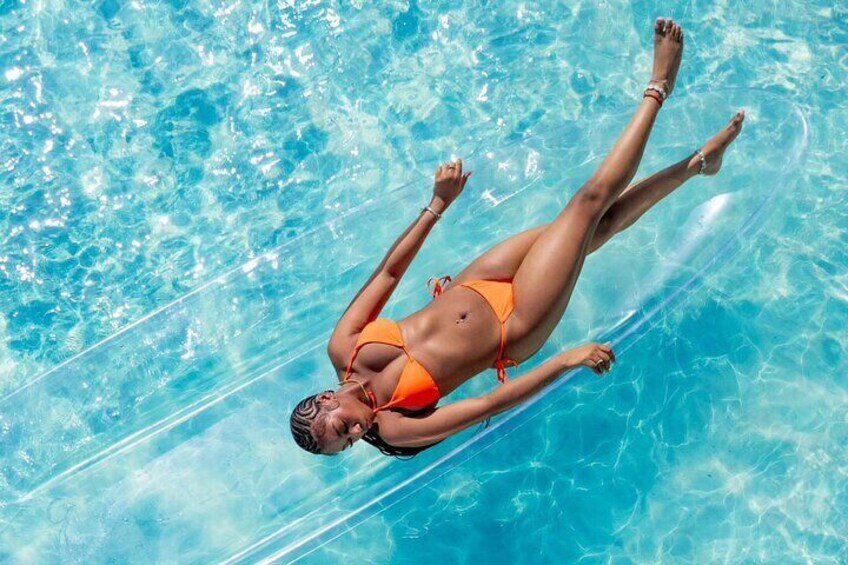Une personne flotte sur un matelas gonflable dans une piscine à l’eau cristalline et d’un bleu éclatant. 1