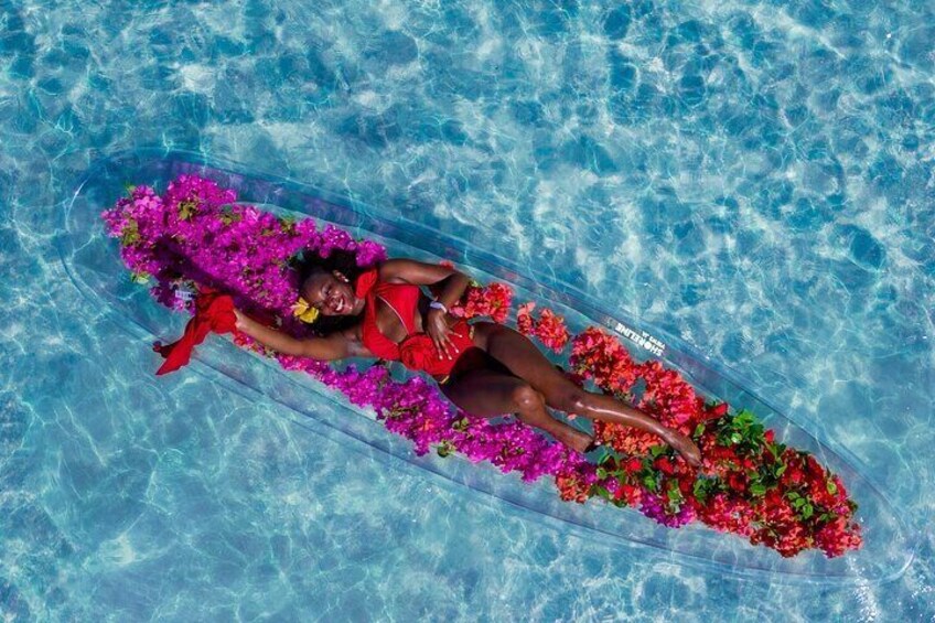 Une personne flottant dans une piscine, entourée de fleurs aux couleurs vives. 2